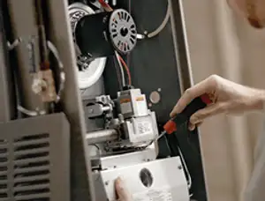 Furnace repair technician inspecting internal components and wiring in Spokane, WA