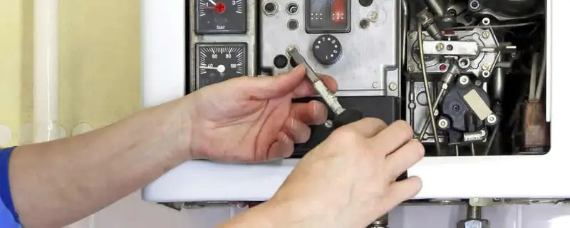 Heating repair technician adjusting boiler controls and components in Spokane, WA