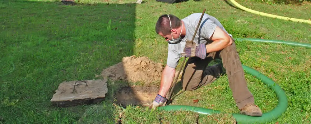 Septic pumping technician servicing a residential septic tank in Spokane, WA