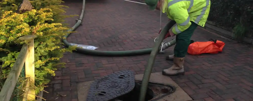 Septic tank cleaning technician servicing a septic tank with a vacuum hose in Spokane, WA