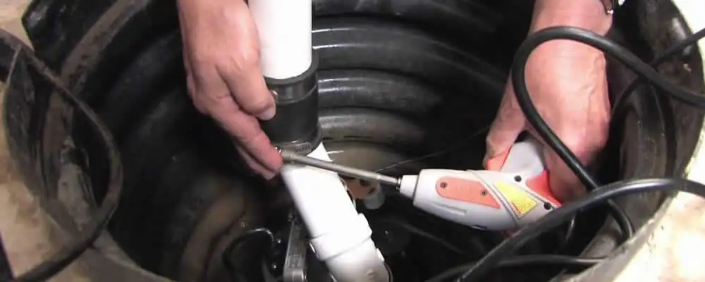Sump pump installation technician connecting PVC discharge piping in Spokane, WA