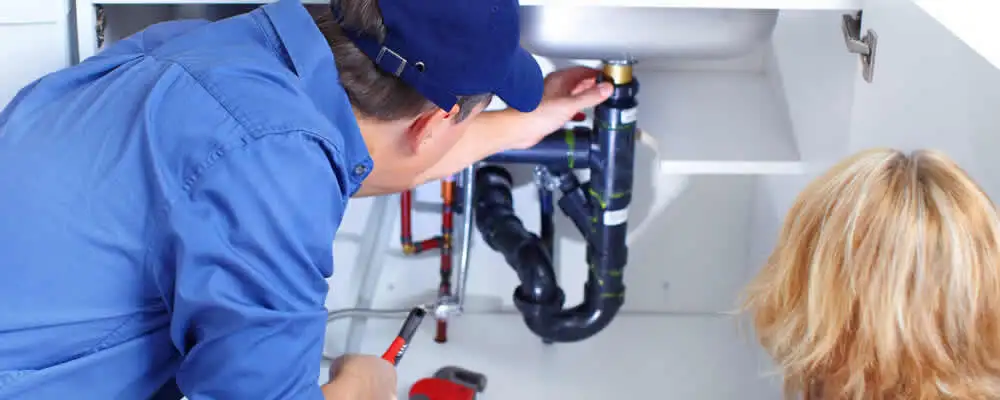 Plumber repairing under-sink drain pipes and fittings in Spokane, WA